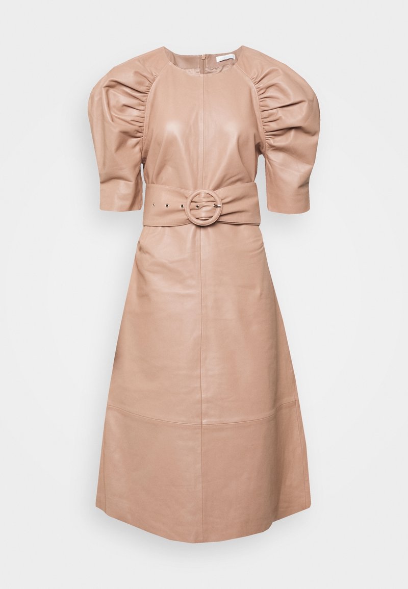 Läderklänning i ljusbeige, med en figursydd livdel, puffärmar och en bälte i midjan med en cirkulär spänne. Slät yta, knälång.