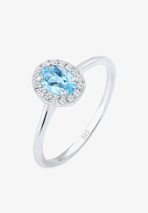 Sølvring med en oval lysblå ædelsten omgivet af en krans af små klare sten. Glat ring med en poleret finish.