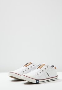 Weiße Leinenschuhe mit glatter Textur, runder Spitze, schnürsenkelfreiem Design, braunen Akzenten auf der Zunge und rot-weiß gestreiften Sohlen.