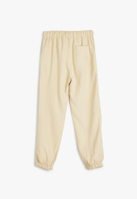 Beige joggers med elastisk talje og samlet manschet, med en enkelt baglomme og en blød, glat stoftekstur.