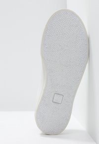 Semelle de chaussure blanche en caoutchouc texturé, avec un design plat et un logo en relief. Matériau lisse avec un style minimaliste et sans motifs visibles.