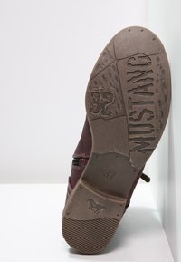 Botín de cuero burdeos con superficie texturada, cierre de cremallera y suela de goma con un diseño embosado de un caballo y la palabra "WUSTANG". Tamaño 37.