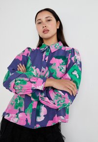 Fargerik langermet skjorte med lilla bunn, og store rosa og grønne blomster mønstre, strukturert stoff, og knappet front.
