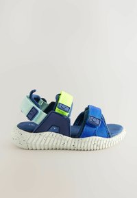 Blaue Sandale mit verstellbaren Riemen in Dunkelblau, Hellblau und Neon-Grün. Sie verfügt über eine gesprenkelte weiße Sohle und ein strukturiertes Fußbett.