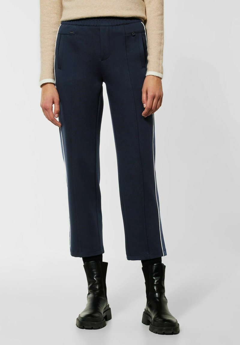 Marineblaue, lässig geschnittene, cropped Hosen mit weißen Seitenstreifen und zwei vorderen Taschen. Hergestellt aus einem weichen, strukturierten Stoff.