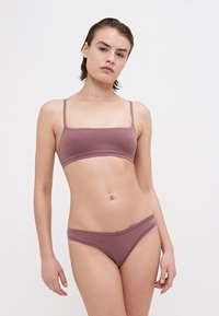 Svetlý mauve podprsenka a zodpovedajúce bikiny vyrobené z hladkej textílie. Podprsenka má tenké ramienka a obdĺžnikový strih. Minimalistický dizajn.