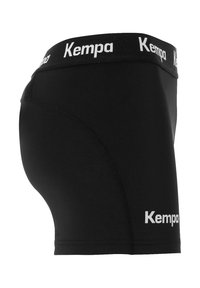 Shorts de compression sportifs noirs avec le logo "Kempa" sur la taille et la cuisse inférieure, vus de côté.