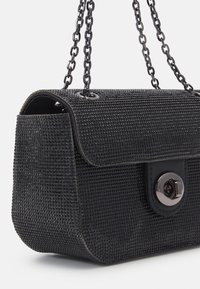 Borsa nera con texture, chiusura a pattina e serratura a scomparsa in argento, dotata di doppi manici a catena in metallo nero.