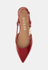 Sandal in pelle verniciata rossa con punta affilata, cinturino sottile e elemento decorativo in metallo. L'interno presenta il logo impresso in oro.