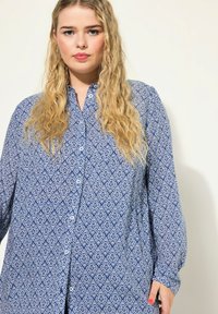 Camicia button-up blu con motivo floreale, maniche lunghe e colletto classico; realizzata in un tessuto leggero.