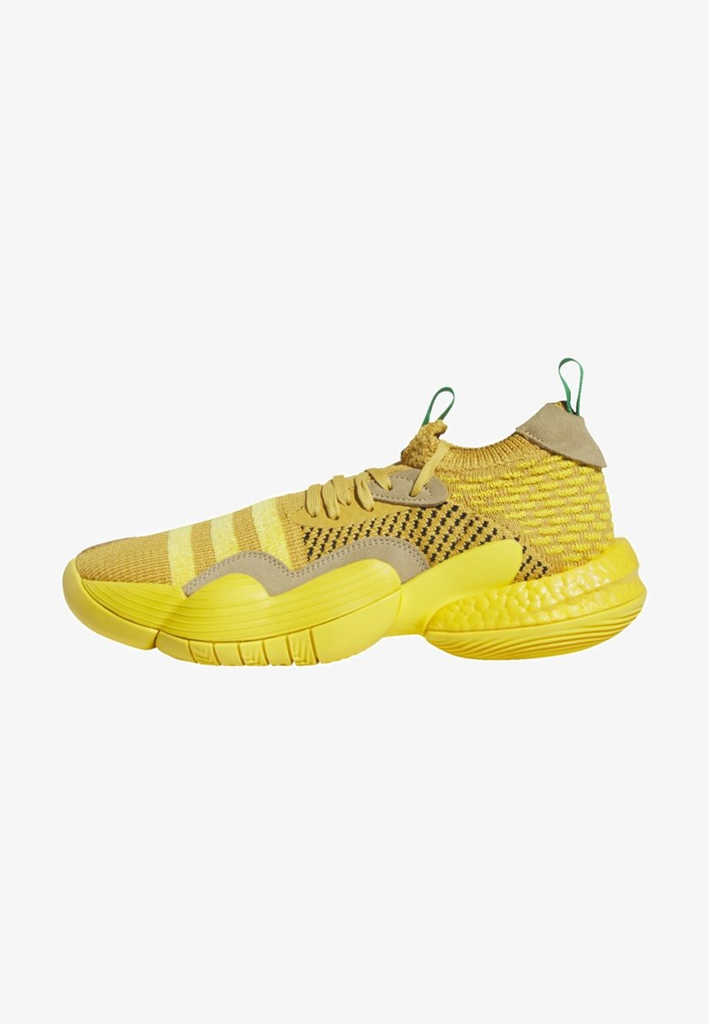 Basket jaune tricotée pour le sport avec une semelle texturée, des accents beige, un laçage à l'avant, et des languettes vertes sur la languette et le talon.