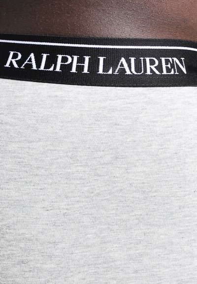 Grijze stoffen tailleband met zwarte rand waarop de witte tekst "RALPH LAUREN" staat; een geweven patroon is zichtbaar op de tailleband.