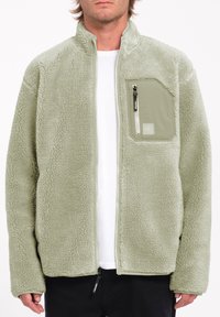 Fleece jack in lichtgroen, met een volledige ritssluiting, hoge kraag en een ritsborstzak. Gevoed stof en een ontspannen pasvorm.