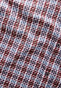 Hemd zum Knöpfen mit einem Karo-Muster in den Farben Rot, Blau, Grün und Weiß. Baumwollstoff mit weicher Textur, versehen mit einem grauen Knopfdetail.