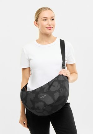 Bolso de hombro negro con un patrón texturizado oscuro, forma curvada y correa ajustable. Presenta un detalle del logotipo en la parte frontal.