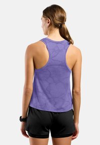 Paarse tanktop met een gewatteerd patroon, ronde halslijn en racerback-design, gecombineerd met zwarte shorts. Zacht materiaal, sportieve snit.
