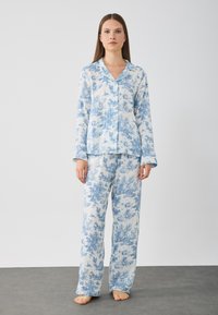 Blå och vit blommönstrad pyjamasuppsättning som består av en skjorta med knappar och långa ärmar samt matchande löst sittande byxor.