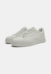 Helle graue Sneakers aus glattem Wildleder, mit einem Low-Top-Design, abgerundeter Spitze, flachen Schnürsenkeln und dezenten Perforierungen.