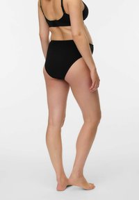 Augsta vidukļa melnas kokvilnas apakšbikses ar gludu tekstūru, bez redzamiem rakstiem vai metāla elementiem, parādītas no sānskata.