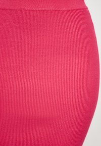 Fustă strânsă, cu model ribbing, într-o nuanță vibrantă de roz. Fabricată dintr-un material elastic, cu o textură netedă și un model vertical consistent.