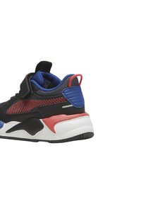 Sneaker sportivo nero con accenti rossi e blu, tomaia in mesh testurizzato, colletto imbottito e suola bianca, dotato di una fascia con chiusura a strappo.