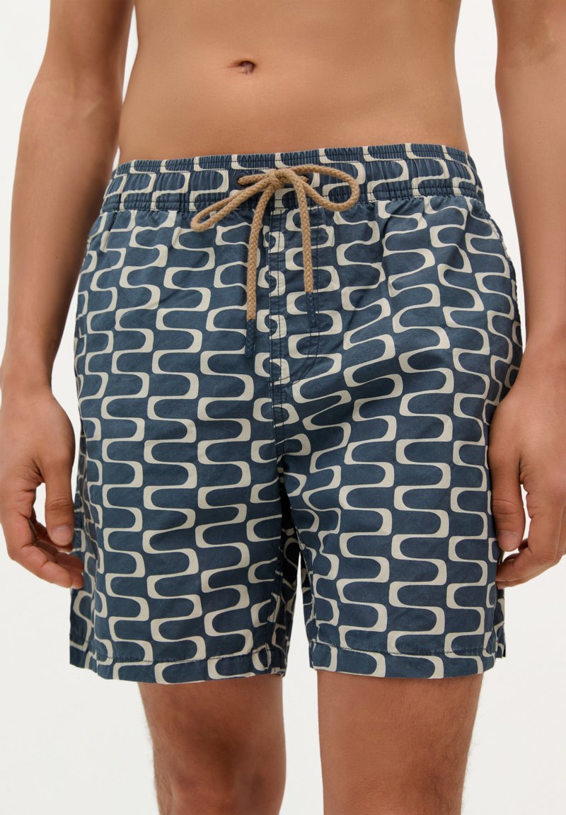 Shorts de bain à motif bleu avec un design abstrait crème, une taille élastique avec cordon de serrage, et une texture de tissu léger.