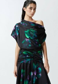 Crna haljina s nabranošću, ukrašena zelenim i ljubičastim cvjetnim uzorcima, s mekim naborima i asimetričnim dizajnom bez ramena.