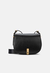 Melnas ādas crossbody soma ar noapaļotu formu, zelta detaļu akcentiem un logotipa elementu priekšpusē. Iekļauts regulējams siksniņa.