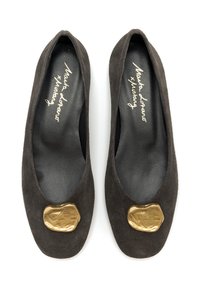 Zapatos planos de ante marrón oscuro con punta redonda, que presentan un acabado texturizado dorado en la parte superior. Plantilla negra con marca blanca.