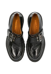 Schwarze Lacklederschuhe mit runder Spitze, ausgestattet mit einem breiten Riemen und metallischen Schnallenakzenten. Braunes Innenfutter mit eingeprägtem Markennamen.