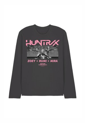 Dark long-sleeve shirt with pink text "HUNTRAX," three female characters in dance poses, and names Zoey, Rumi, Mira, Kpop Demon Hunters below.