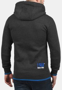 Szary hoodie z kapturem z niebieskimi akcentami na mankietach i dolnym brzegu. Zawiera detal logo w niebieskim i białym na dolnej części pleców. Miękka tekstura.
