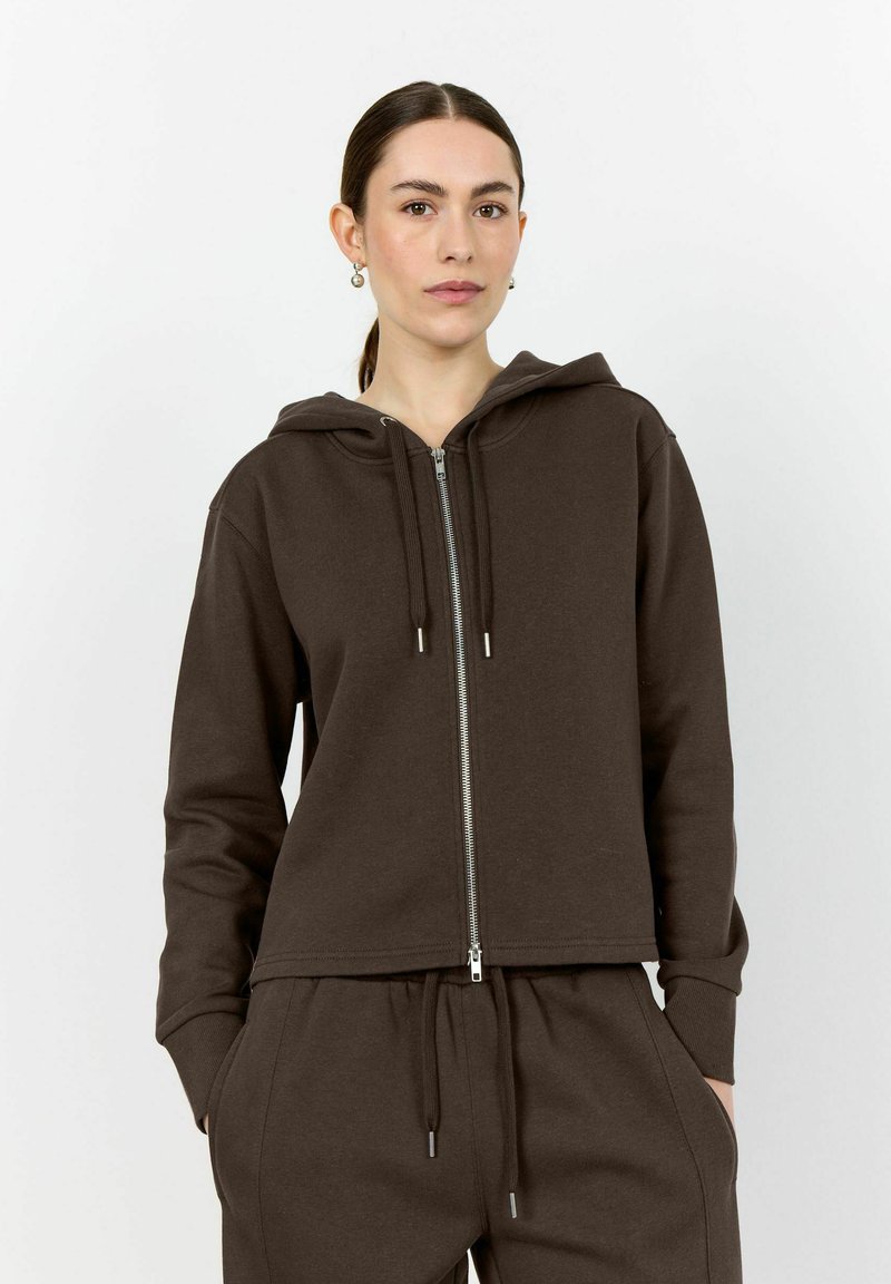 Brown zip-up hoodie with a drawstring hood, featuring a relaxed fit, ribbed cuffs, and smooth texture, paired with matching pants.
