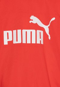 T-shirt en coton rouge avec un logo "PUMA" blanc bien en vue et un graphisme de puma en train de sauter, texture lisse et design décontracté.