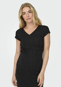Crna, uska haljina s V-izrezom i kratkim rukavima. Ima nabrane detalje na struku i teksturiranu tkaninu. Glatki, elegantni dizajn.