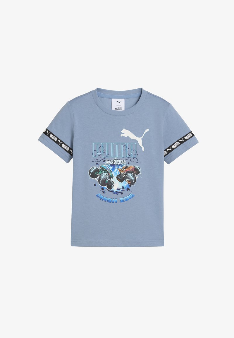 Šviesiai mėlynas vaikų marškinėliai su Puma logotipu, monsterių kamščiai centre ir juodas Puma prekės ženklas juostelė ant rankovių.