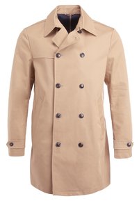 Beige dubbelknäppt kappa i mjukt tyg, med stora mörka knappar, två sidofickor och en slagkrage med klassisk design.