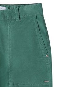 Zelené bavlněné šortky s hladkým povrchem, charakterizované bočními kapsami, stříbrným knoflíkem jako akcentem a malou kovovou logovkou na lemu.