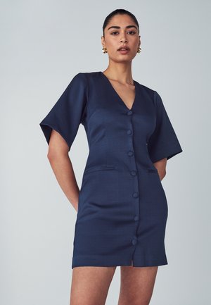 Navy button-up dress with short sleeves, v-neckline, two front pockets, and a textured fabric. Fitted silhouette with a hem above the knee.