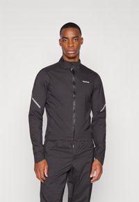 Schwarze leichte Jacke mit hohem Kragen, Frontreißverschluss und reflektierenden Akzenten an den Ärmeln. Hergestellt aus einem glatten, wetterbeständigen Stoff.
