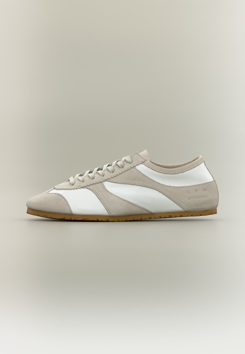 Χαμηλού προφίλ αθλητικό παπούτσι με επικάλυψη μπεζ σουέτ, λευκά δερμάτινα πάνελ, μπεζ κορδόνια και καουτσούκ σόλα, εμφανιζόμενο σε πλαϊνή όψη σε ουδέτερο φόντο.