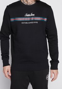Felpa nera in cotone con maniche lunghe, caratterizzata da un collo tondo, righe orizzontali verdi e rosse, e il logo "Jack & Jones Established 1990".