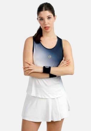 Vrouw met een donkere paardenstaart, gekleed in een mouwloos sporttopje met blauwe en witte gradient en een witte rok, met gekruiste armen en zwarte polsbandjes.