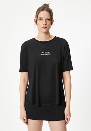 T-shirt noir avec une coupe décontractée, des manches courtes et un col rond. Un texte blanc sur le devant indique : « SEUL VOUS POUVEZ DÉFINIR VOS LIMITES. »