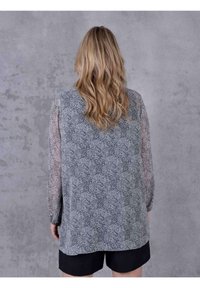 Halenka s dlouhým rukávem má šedý paisley vzor, lehkou látku a průsvitné rukávy. Lem je mírně delší vzadu.