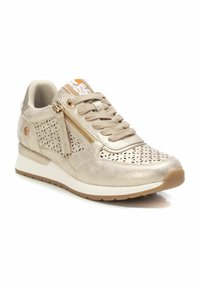 Zapatilla deportiva de color dorado metálico con diseño perforado, parte superior texturizada, cierre de cordones y cremallera, suela acolchada y suela de tracción de goma.