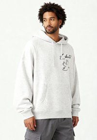 Felpa con cappuccio grigio chiaro in morbido misto cotone con tasca a marsupio, con un disegno lineare nero di un uccello e la parola "Liberté".