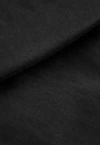 Tela negra con una textura mate y suave, que muestra capas dobladas. La superficie tiene un ligero estriado, indicando que es un material de mezcla de algodón.