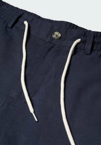 Pantalon bleu marine avec fermeture boutonnée cousue, ceinture élastique, passants pour ceinture et cordons blancs avec embouts métalliques.