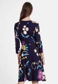 Námořnické šaty s tříčtvrtečními rukávy, zdobené živými květinovými vzory v různých barvách a kulatými akcenty. Měkká, elastická látka.